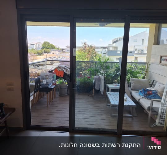ויטרינת הזזה מאלומיניום כהה המוליכה למרפסת שמש
